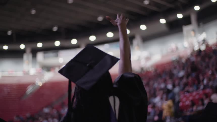 A female graduate waves to the audience during a graduation ceremony