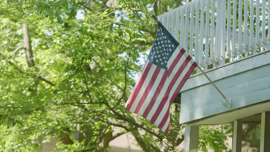 American flag attached to building balcony flaps in breeze
