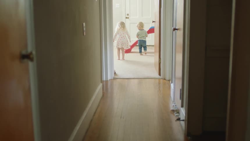 Kids play in carpeted room at end of wooden floored corridor