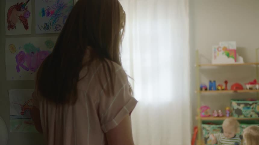 Mother watches children playing together in room