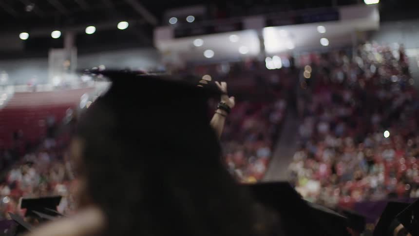 A graduate is waving at a crowd