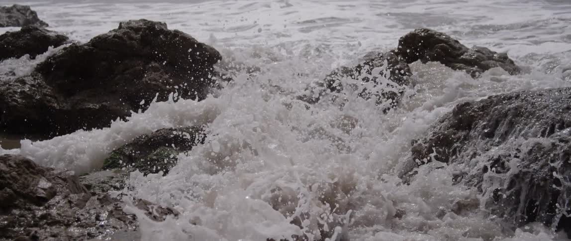 A wave crashes over rocks