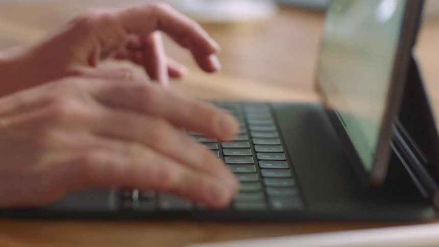 Two hands typing on a keyboard