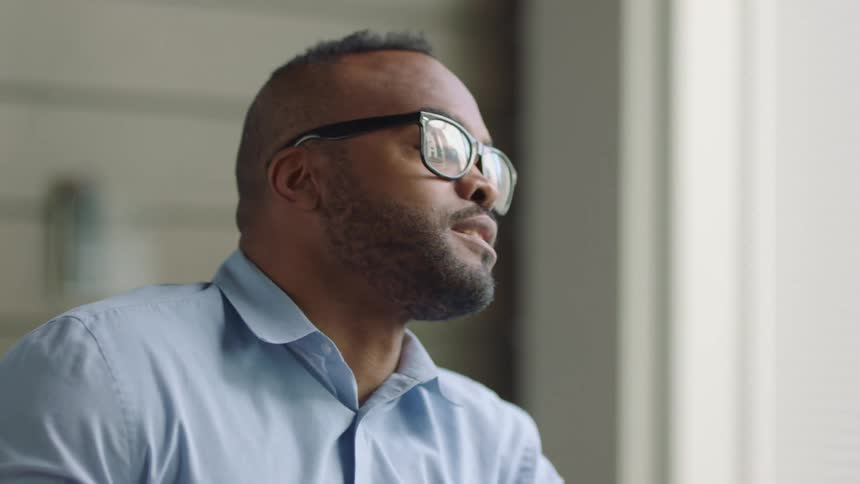 A man with glasses talking and drinking coffee during meeting
