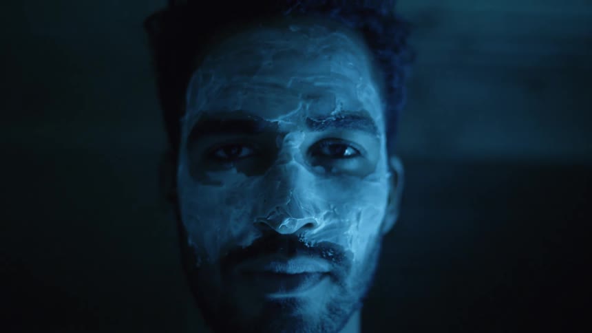 A man with his face slathered in lotion opens his eyes