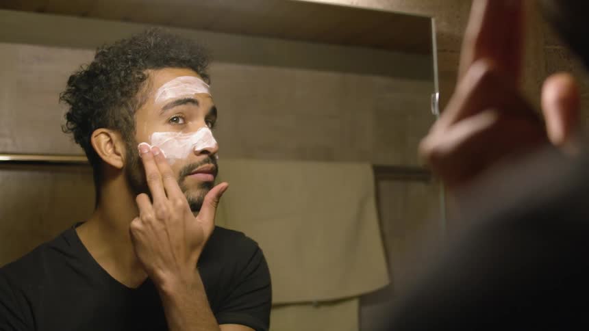 A man is putting skin cream on his face