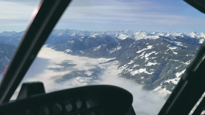 A helicopter flying over a snowy mountain range on a winter day
