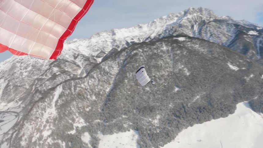Paragliders soaring over snowy mountains on a winter day