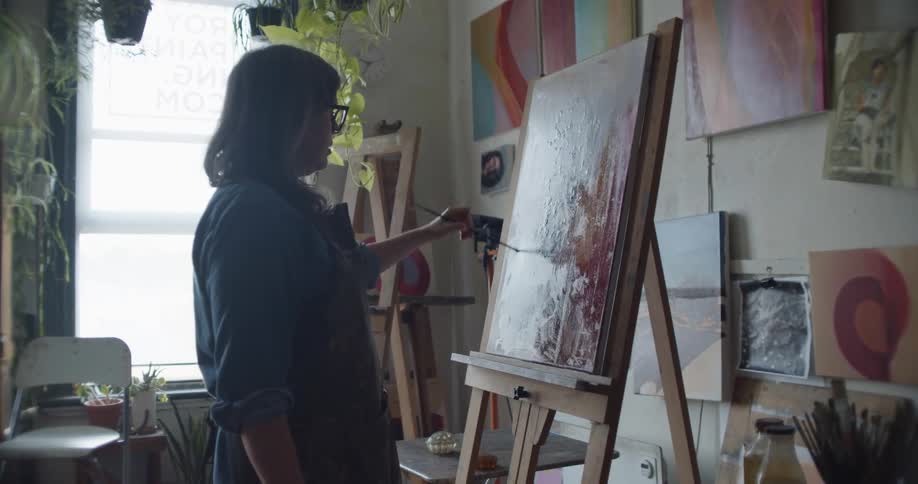 A female artist painting on a canvas in an art studio