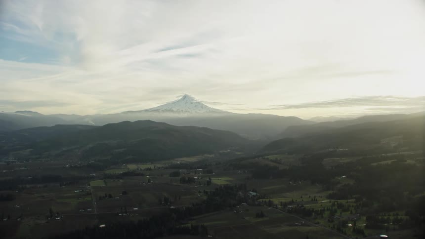Golden afternoon light illuminates agricultural land and a massive volcano in this early spring aerial of Mount Hood near Portland, Oregon