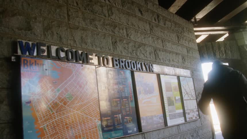 A person walking their dog in a building with brooklyn guides and maps hanging up