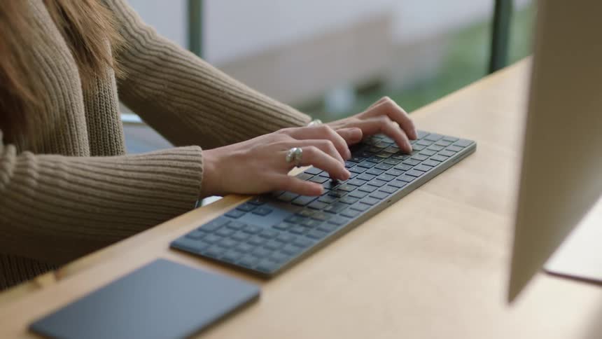 A woman sits down at a desk and starts to type