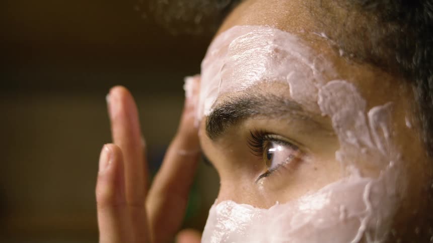 Man applying a face mask on his forehead