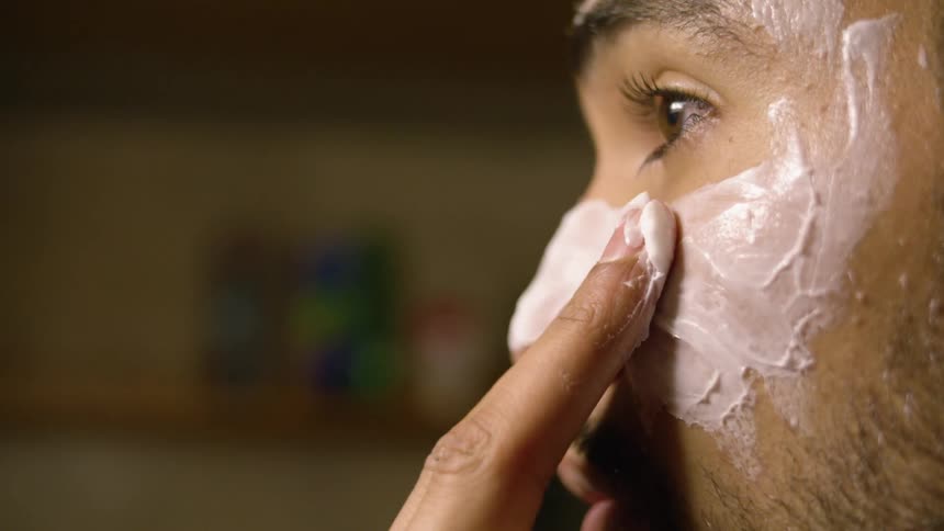 A man is putting skin cream on his face