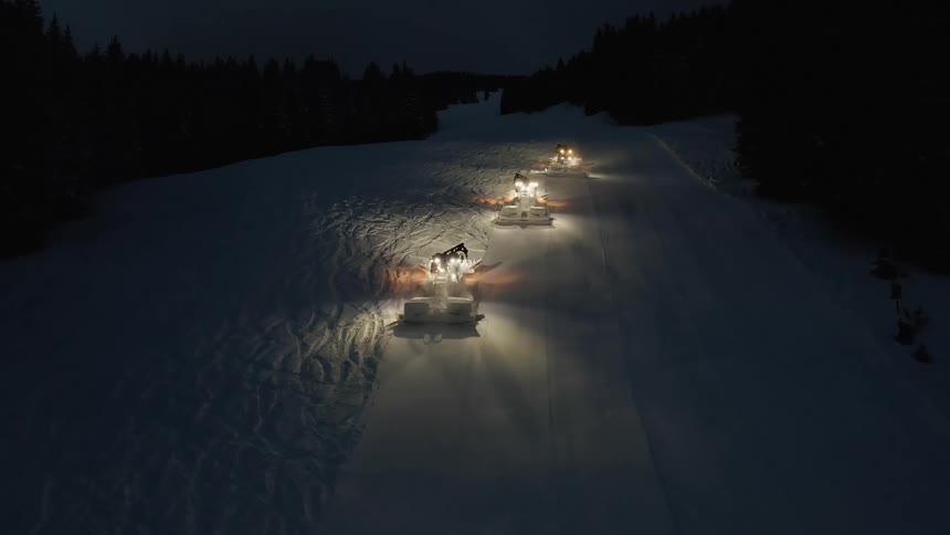 Vehicles plowing snow with trees the sky and clouds in the background