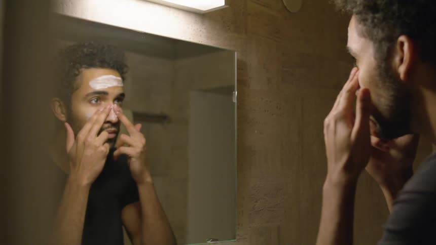 Man applying face moisturizer in the bathroom