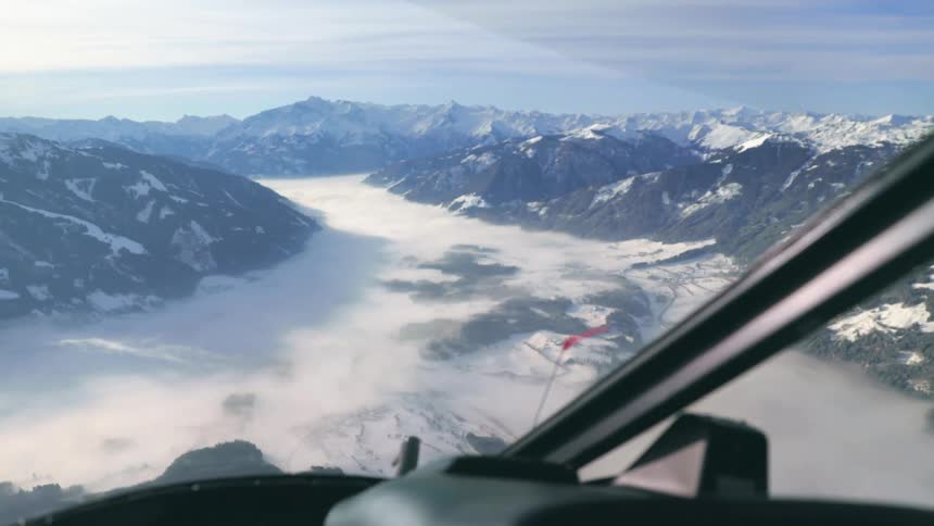The view of mountains and snow from the windshield of a helicopter flying above