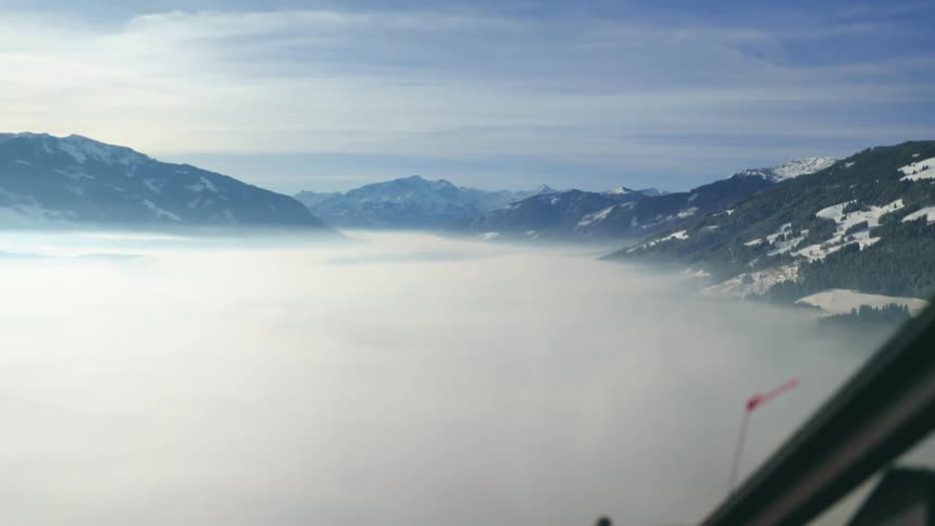 A helicopter flies over the clouds