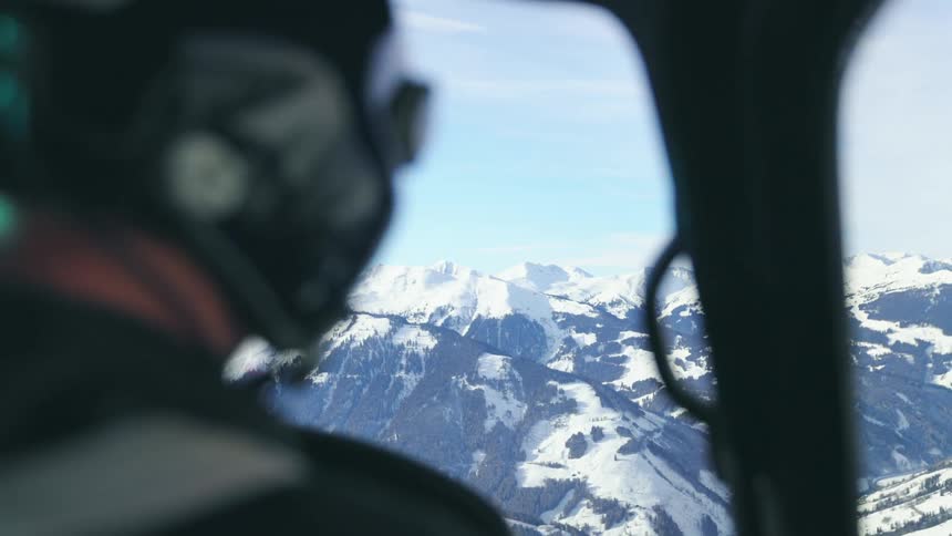 A pilot flies an aircraft of a snow capped mountain range during the day