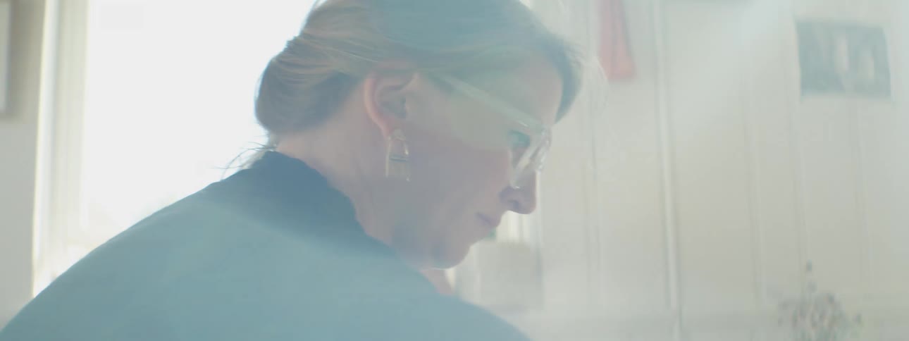 Woman wearing glasses in front of a window under sunlight at home