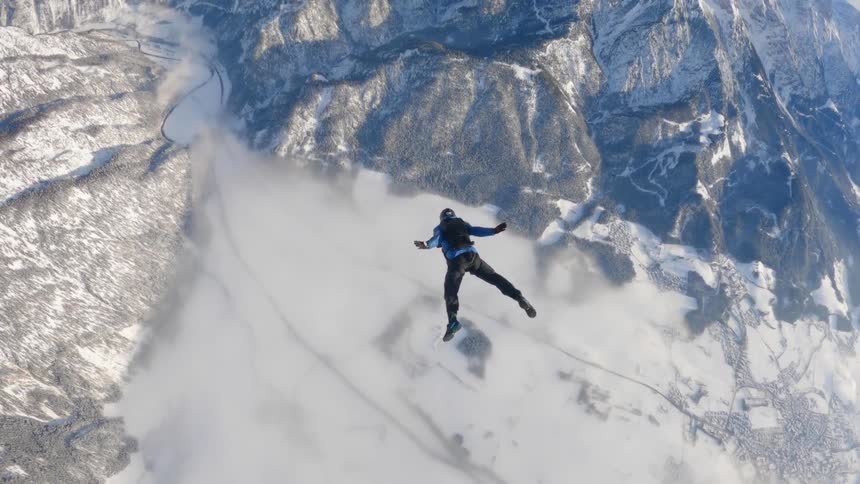 A man is skydiving above the mountains