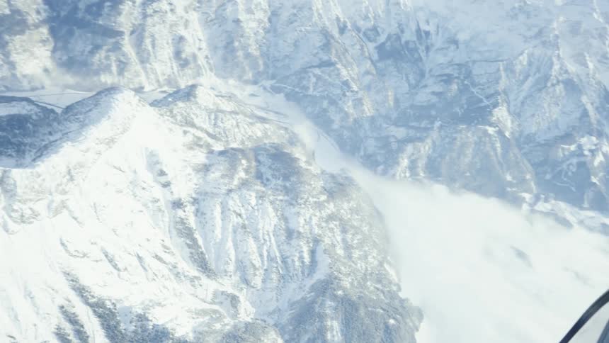 Glass of enclosed cabin reflects snow covered mountains