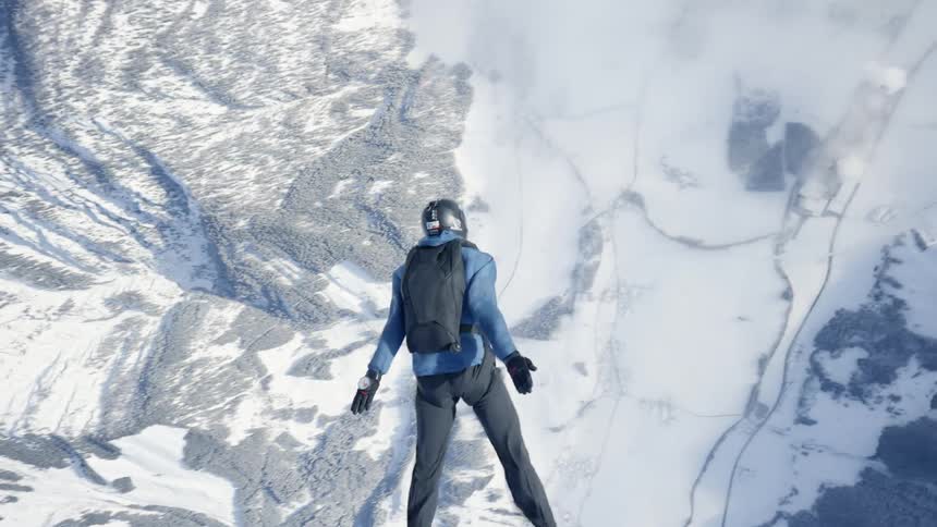 Skydiver wearing a parachute pack and black helmet is floating over a snow covered mountain canyon