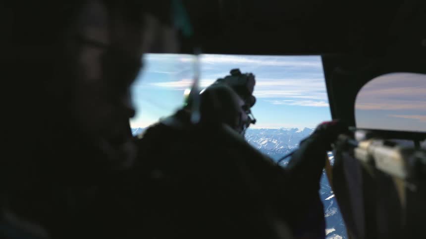 Two people flying in a helicopter looking out
