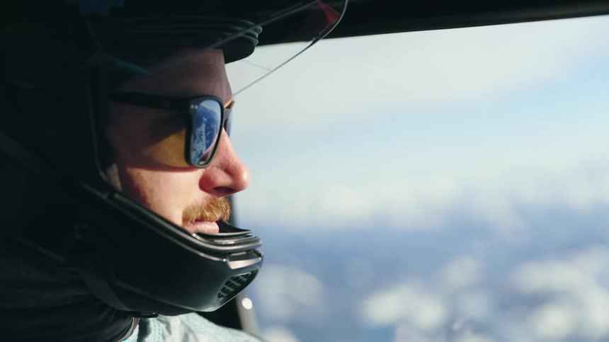A person is driving a helicopter and wearing a helmet
