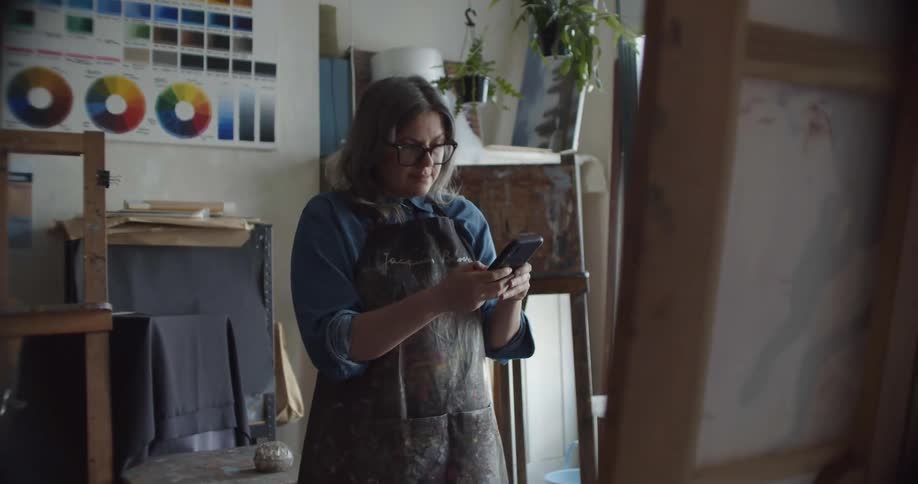 An artist takes pictures of her oil paintings using the smartphone camera inside her studio