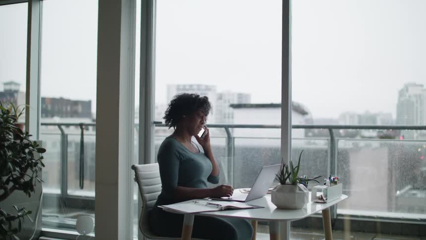 A woman sitting in an office typing on a laptop