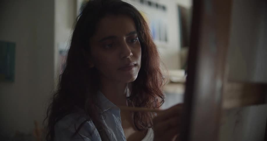 A female artist painting on a canvas in an art studio