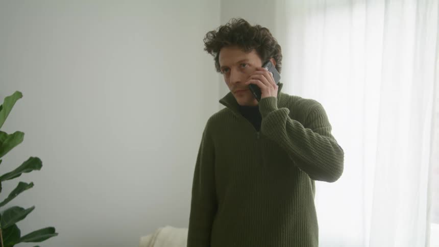 A white male in a sweater makes a phone call from a smartphone
