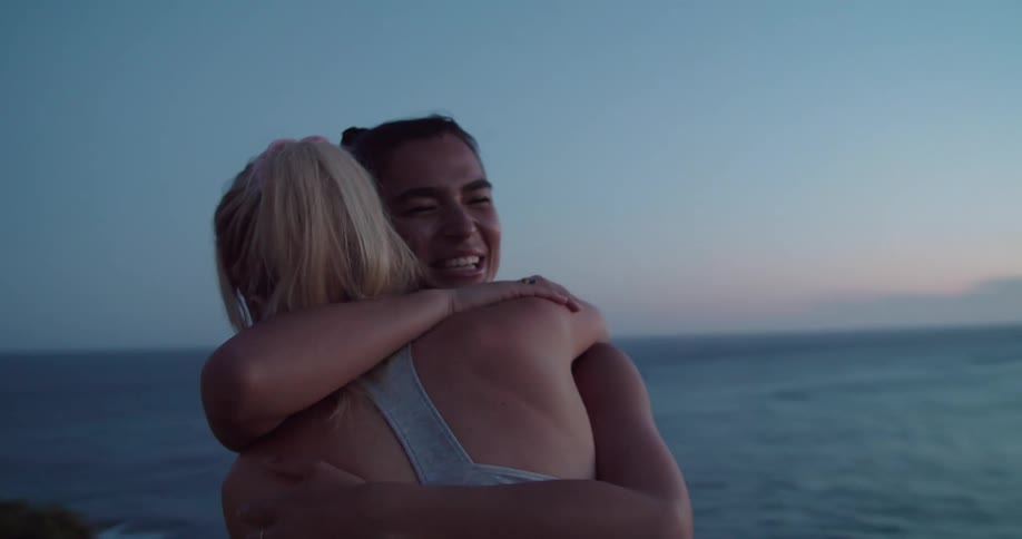 Two women hug on the shore in a neighborhood