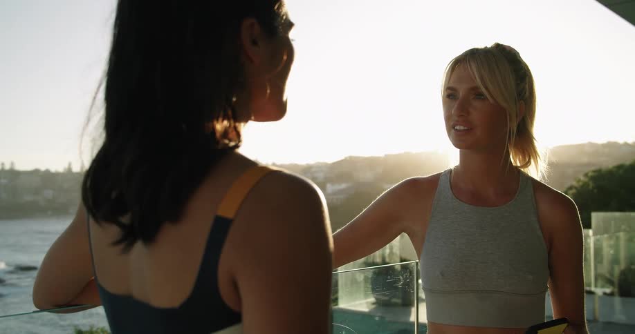 Young fit woman wearing sports clothes talking near a pool in a house at morning