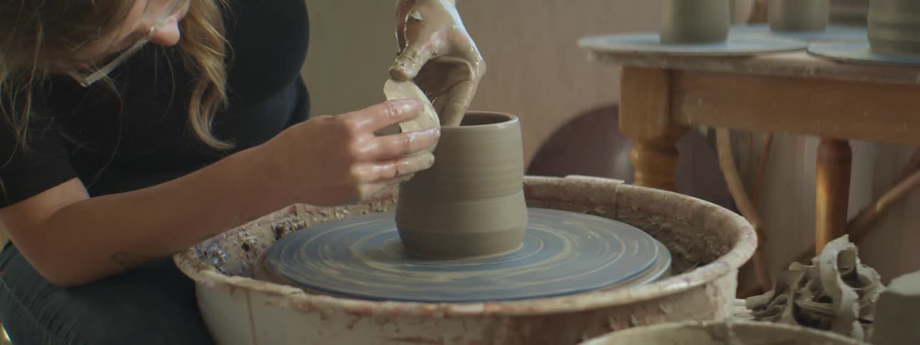 A woman working on pottery on a pottery wheel