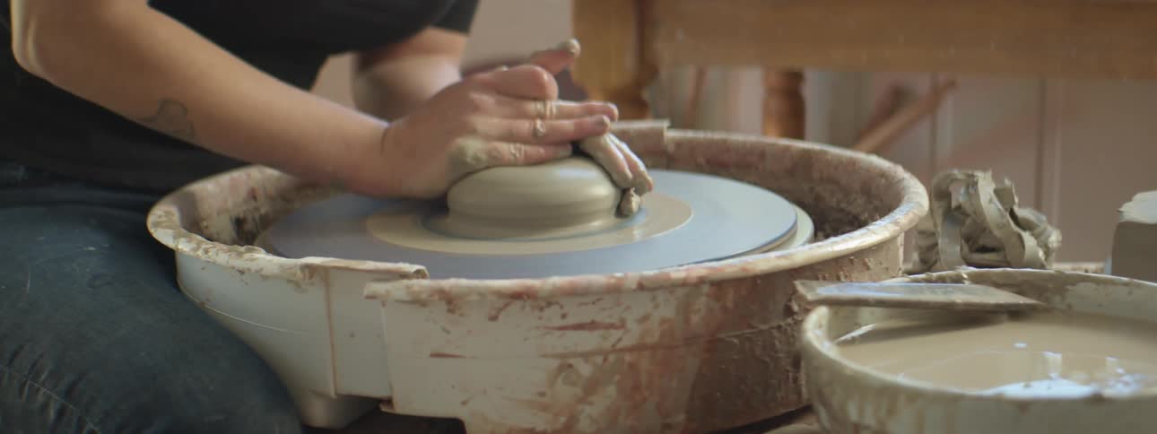 A person is making pottery indoors