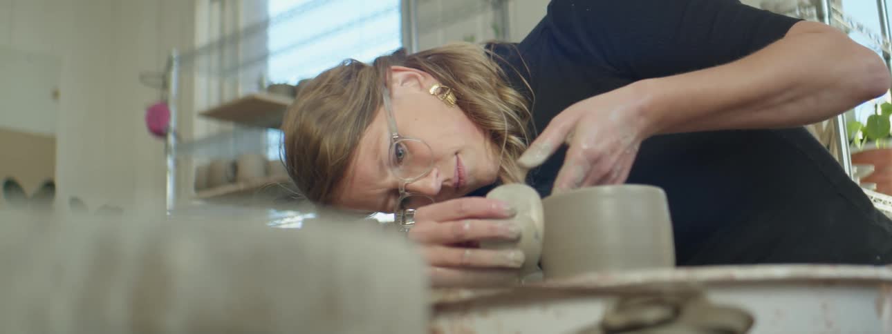 A woman working with clay to make a pot