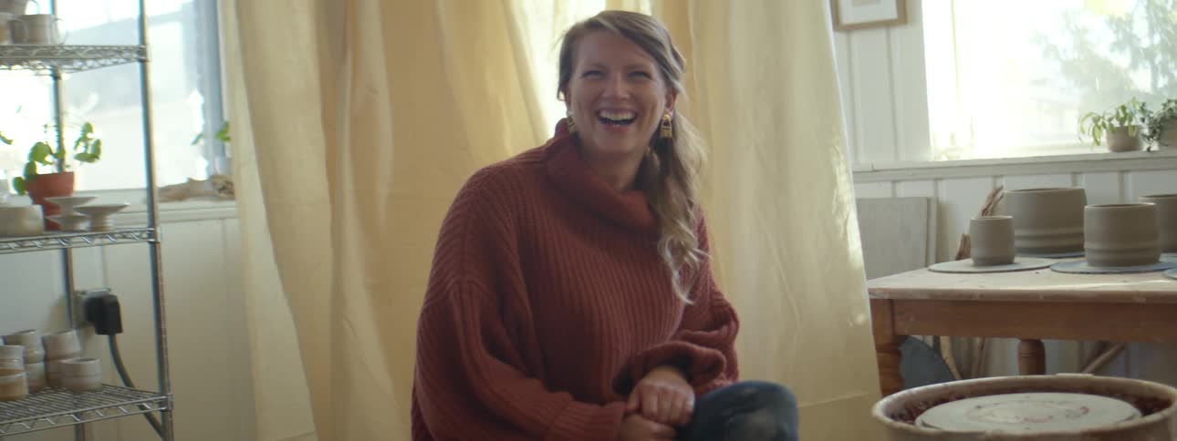 A woman is sitting indoors and smiling