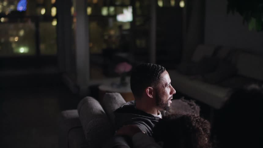 A family watch television on the couch