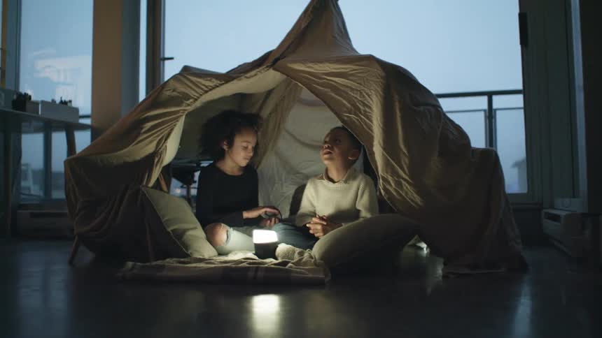 Two children are using a tent in their home