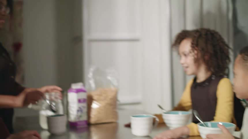 A man a woman a boy and a girl around the kitchen table talking and eating