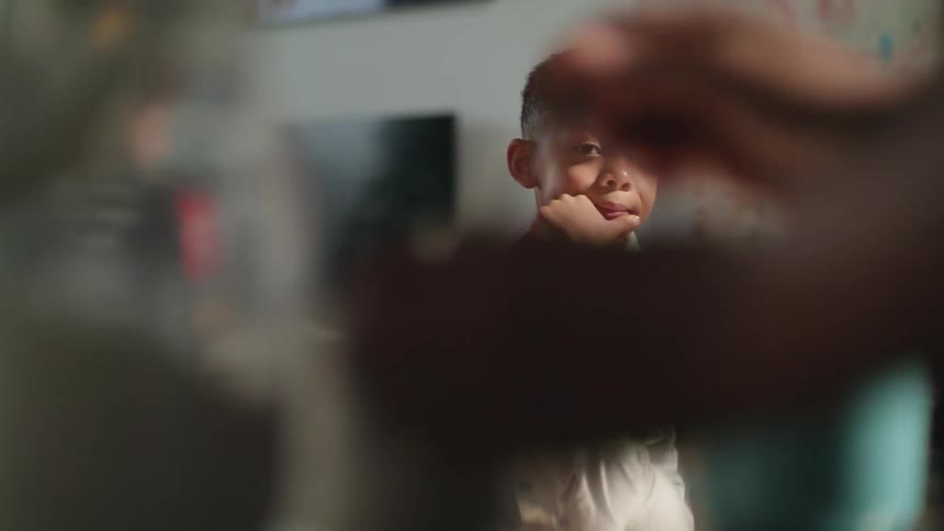 A person stirring a drink in front of a son