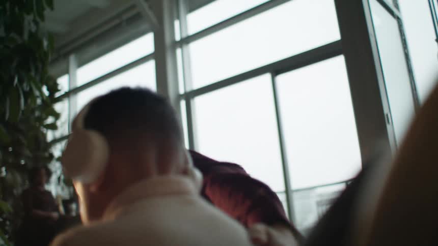 A man at home leans over and kisses his son on the head and pats his back before getting up from the couch and walking away