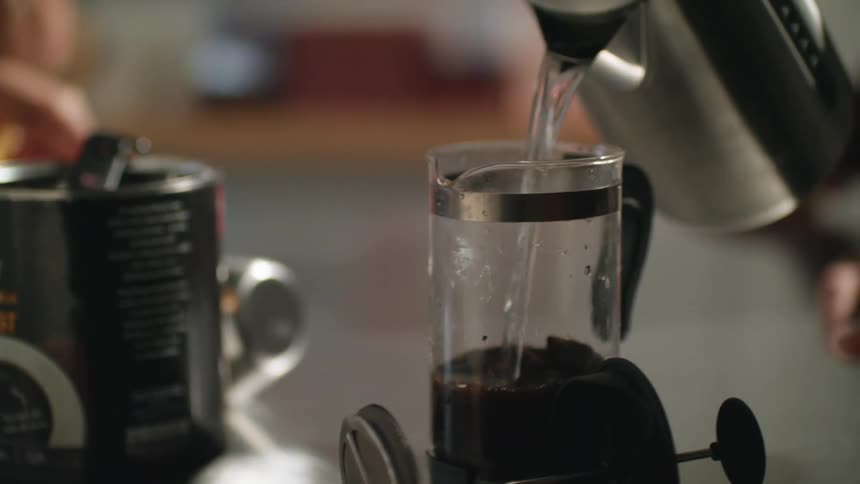 A person pours hot water into a coffee brewer to prepare hot coffee