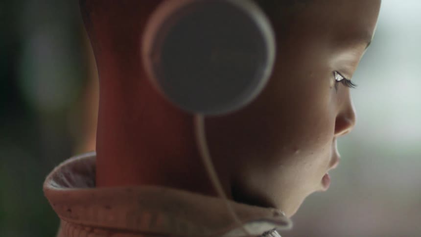 Young boys profile listening with headphones indoors