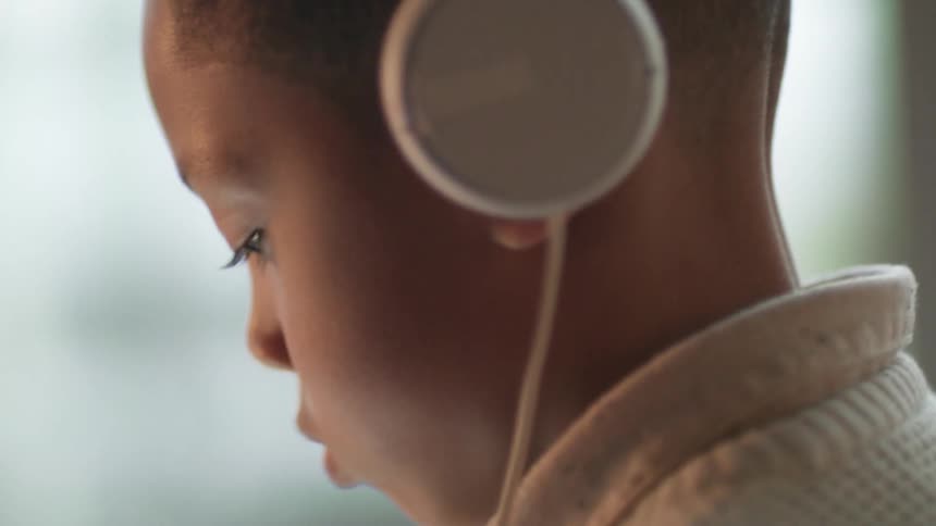 Young boy wearing white headphones sitting in the livingroom at home