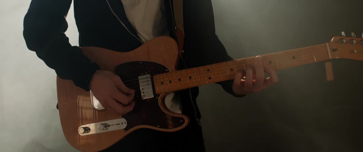 A man playing guitar in a studio with lights and smoke