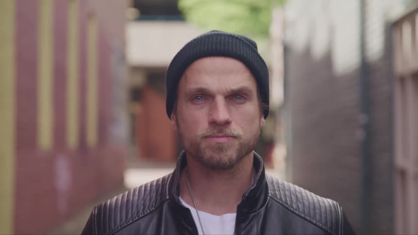 A man standing outside in a leather jacket and beanie