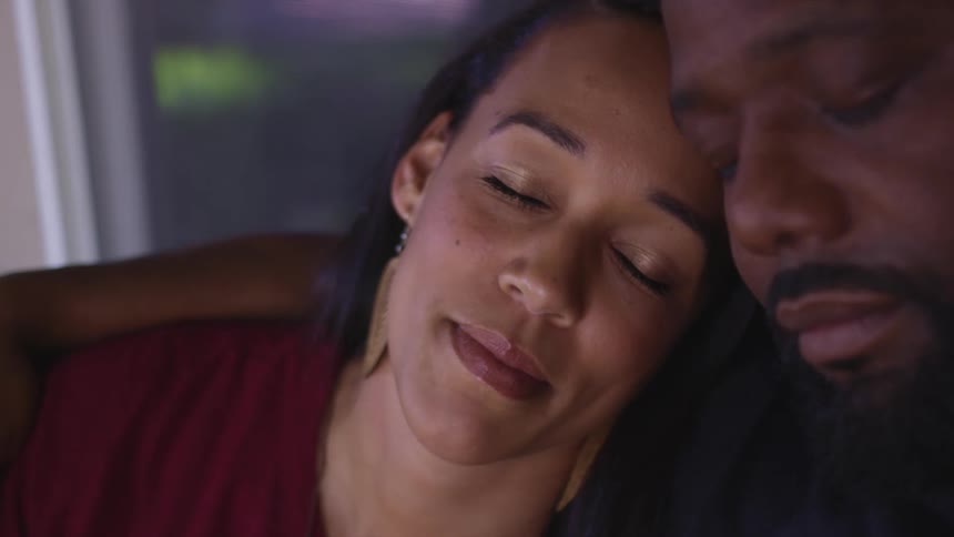 A man and woman resting their eyes while cuddling